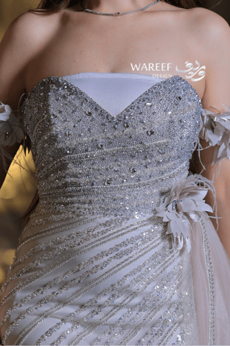 فستان سهرة فضي فاخر بتطريز لامع وأكمام من الريش ال...