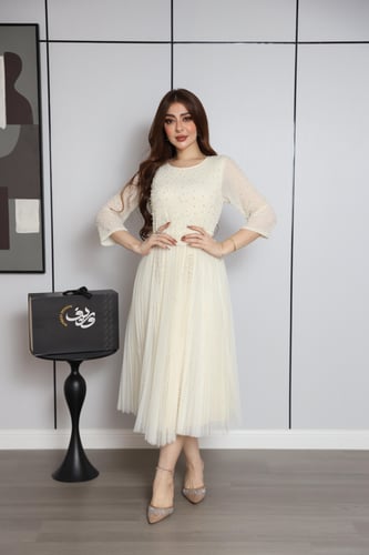 فستان أوف وايت بتطريز ناعم وتنورة بكسرات أنثوية