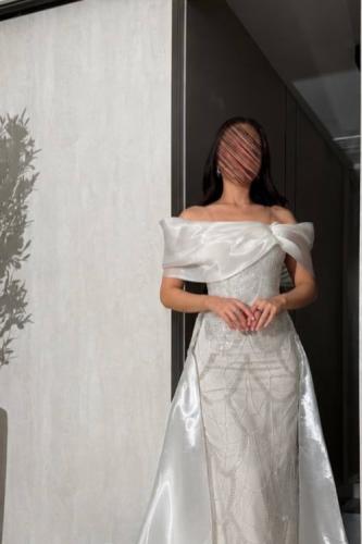A long white dress characterized by elegant shiny embroidery