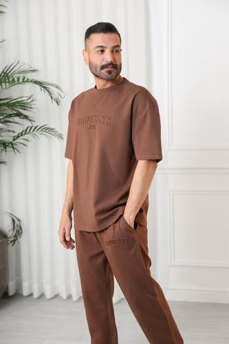 طقم رجالي اوفر سايز نص كم بنطال طويل وياقة دائرية مزين بطبعة نافرة بمنتصف التيشرت ويسار البنطال