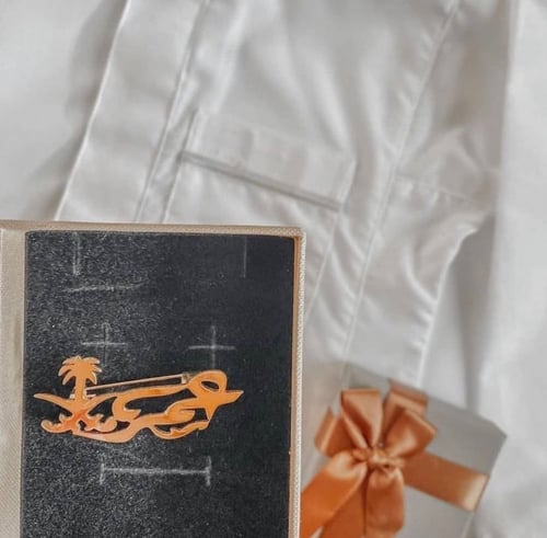 بروش بالاسم بجانب شعار السيفين والنخلة