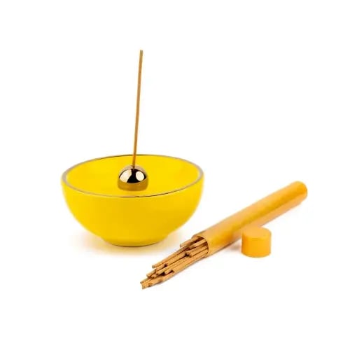 A yellow round incense burner display with a luxurious oud