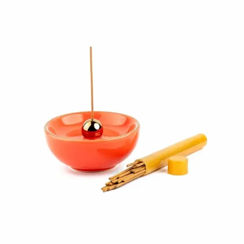 A round orange incense burner with a luxurious incense stick