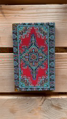 مُفكرة صغيرة بغلاف السجاد مزخرف احمر.