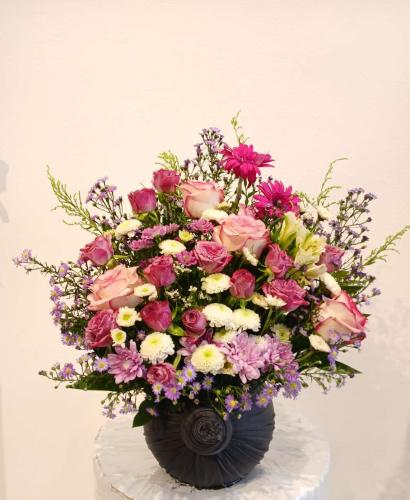 Oval vase wrapped in gray fabric with a natural fl...