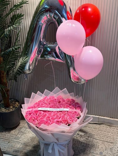 A bouquet of flowers with a balloon and a letter o...