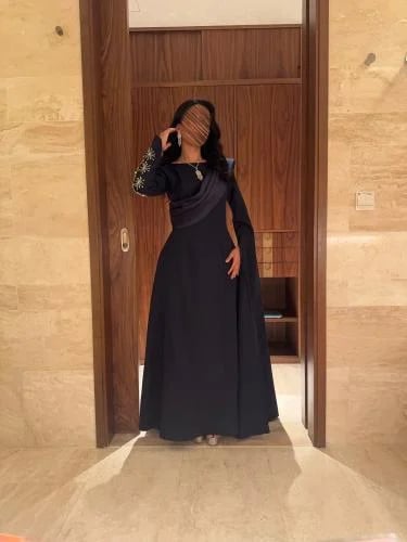 فستان سهرة كحلي بأكمام طويلة وتطريز ذهبي مع وشاح درابيه مائل وتنورة انسيابية