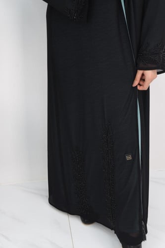 عباية سوداء مبطنة بقماش بلون تركواز مع تفاصيل مطرز...