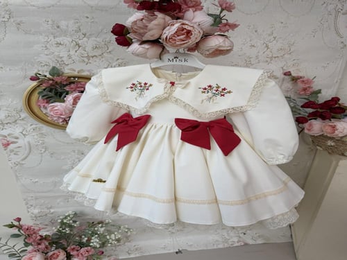 فستان كريمي بفيونكات حمراء