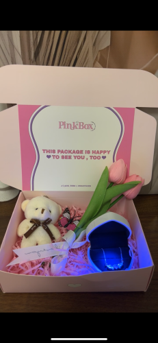 A luminous box with a pink wing necklace, a word, and a teddy bear