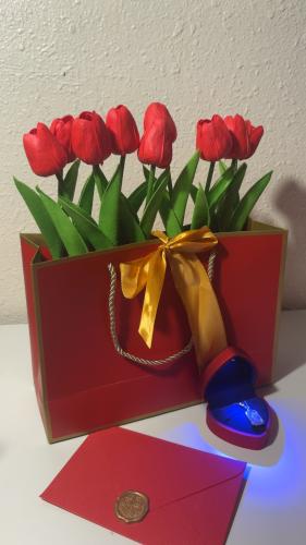 Red bouquet of flowers with a necklace and a card with a phrase attaching the message with the note