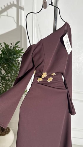 فستان بني طويل بكتف واحد مزين بورود ذهبية أنيقة