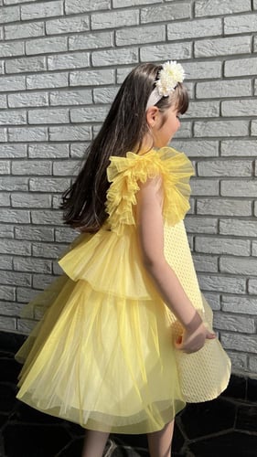 فستان اصفر جاكارد منقط مع طبقات من التل في الخلف