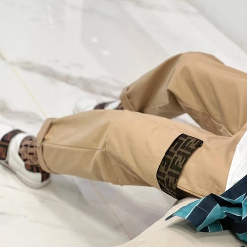 بنطلون بيج من قماش الجبردين عليه شعار للماركة