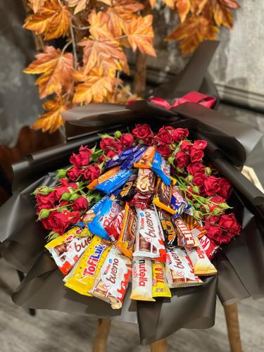 تشكيلة منوعة من الحلويات مرتبة داخل بوكيه مع ورد ب...