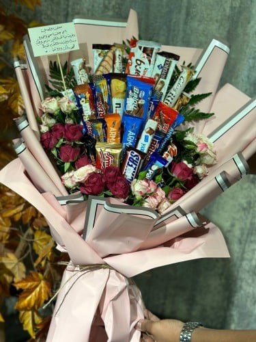 تشكيلة منوّعة من الحلويات المفرحة منسقة وسط بوكيه...