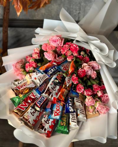 تشكيلة منوعة من الحلويات مرتبة داخل بوكيه مع ورد ب...