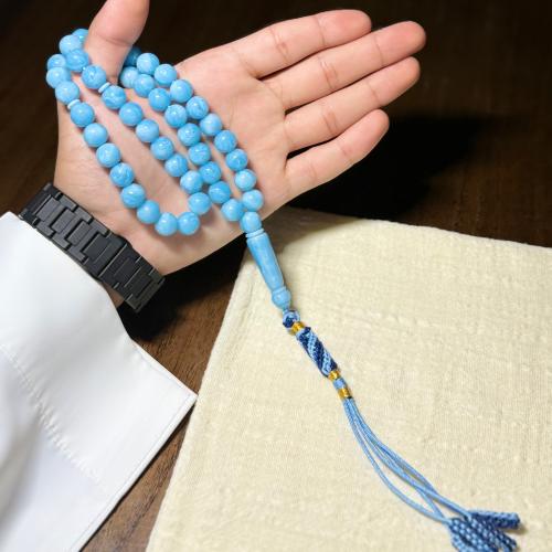 A prayer bead with a clasp, chain, and tassel.