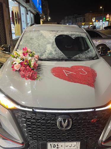 A groom's car decorated with pink roses and a red...