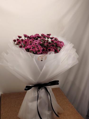 An elegant purple flower bouquet with a small cake...