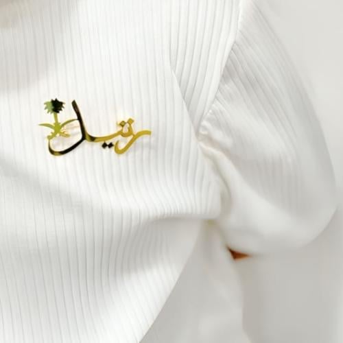 بروش باللأسم وشعار المملكة سيفين والنخلة .