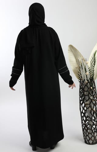 عباية سوداء بتداخل قماش وفصوص فضية طولية وعلى الكم...