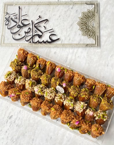 تمر محشي ومزين بالمكسرات في علبة تهنئة عساكم من عو...