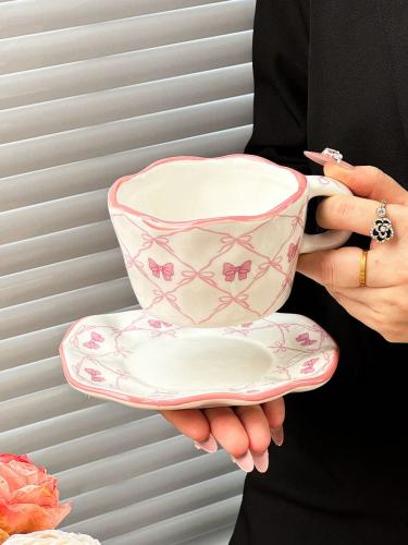 A set of pink ceramic cups and plates with a bow ribbon