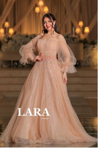 فستان يفيض أنوثة وأناقة، مصمم بلون لحمي ناعم يوحي...