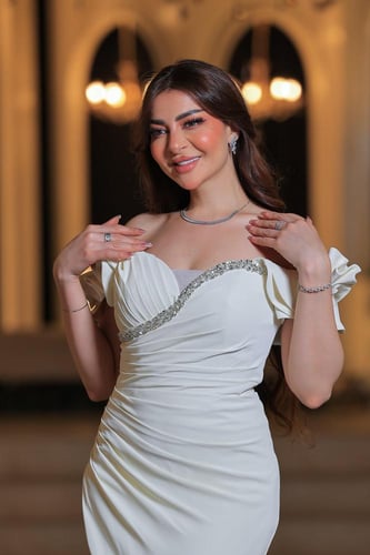 فستان أنيق وفخم، يتميز بتصميم طويل بلون أبيض ناصع...