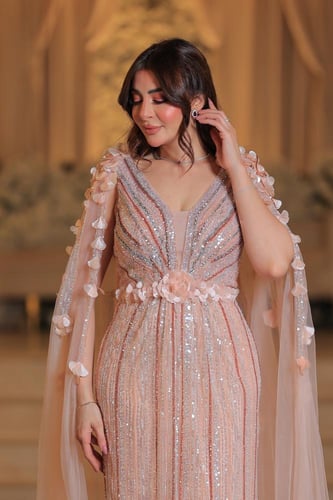 فستان سهرة طويل بلون خربزي يتميز بتصميم اكمام كيب