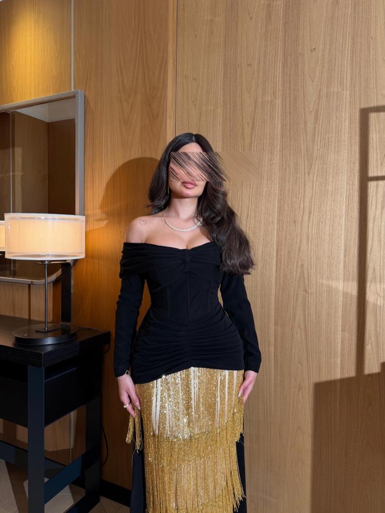 فستان أسود بقصة أنثوية مع شراشيب ذهبية لامعة،