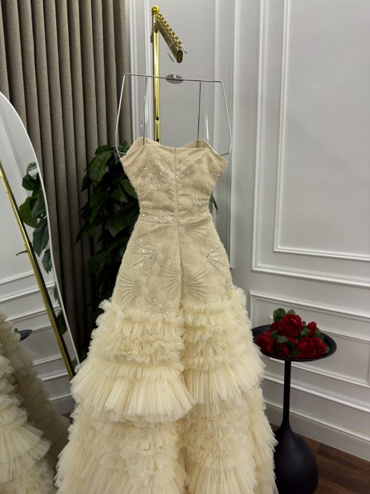 Evening dress in light beige color, decorated with ruffle