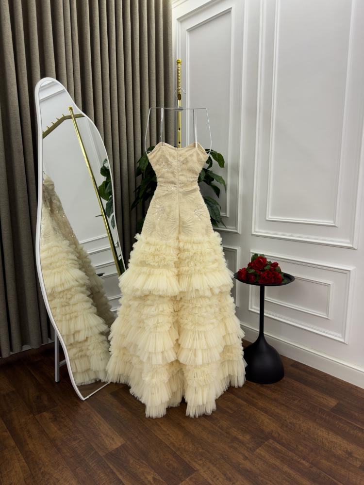 Evening dress in light beige color, decorated with ruffle