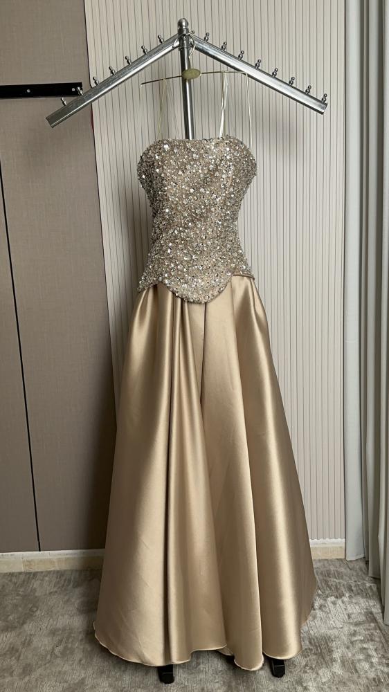 Shima'a dress. Feteet beige dress embodies calm elegance and soft sophistication with an elegant feminine style. The feteet fabric is characterized by its luxurious texture and light shine that reflect light softly, with a high ability to maintain the sha