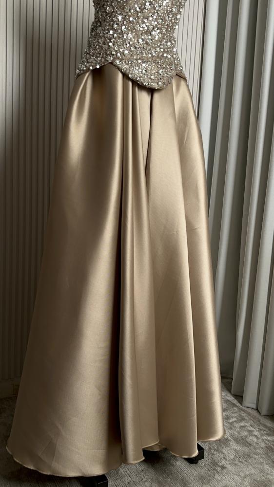 Shima'a dress. Feteet beige dress embodies calm elegance and soft sophistication with an elegant feminine style. The feteet fabric is characterized by its luxurious texture and light shine that reflect light softly, with a high ability to maintain the sha
