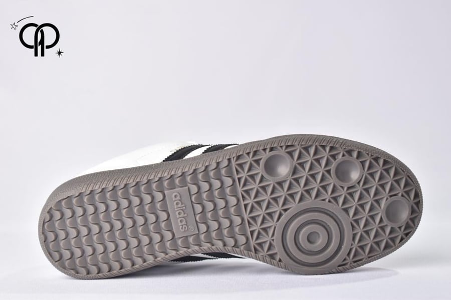 حذاء نسائي اديداس سامبا أسود مع أبيض an Adidas Samba OG shoe in cloud white with core black stripes and a gum rubber sole.