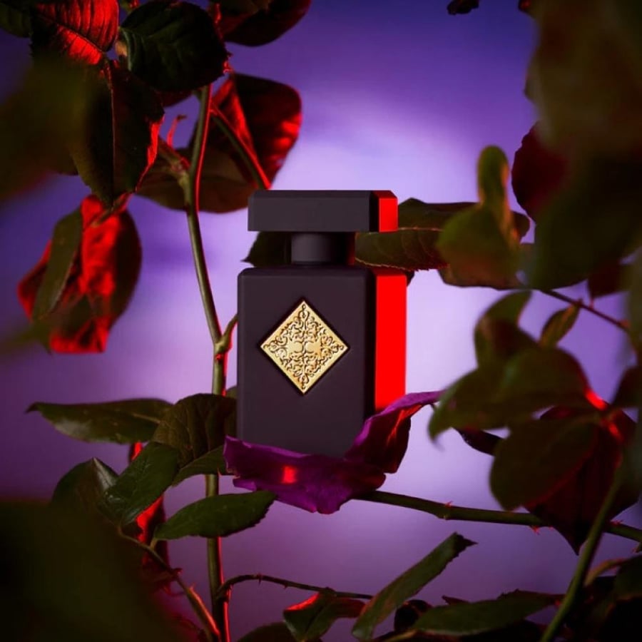 جمال زجاجة عطر Initio Atomic Rose وسط بتلات الزهور البنفسجية