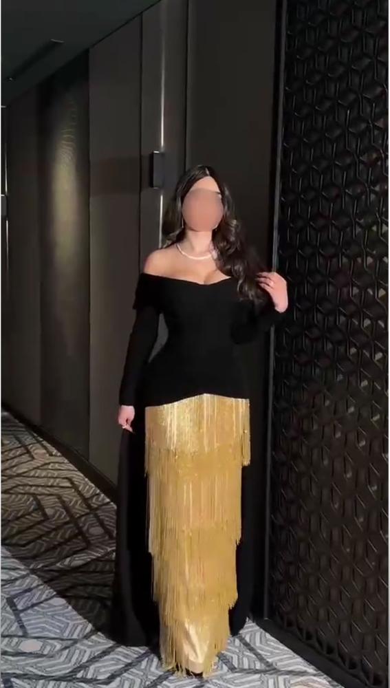 فستان سهرة أسود فاخر بتفاصيل ذهبية متدلية وكتف مكشوف