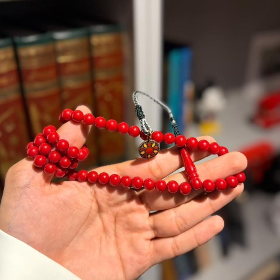 مسباح أحمر بكركوشة الميدالية في راحة اليد