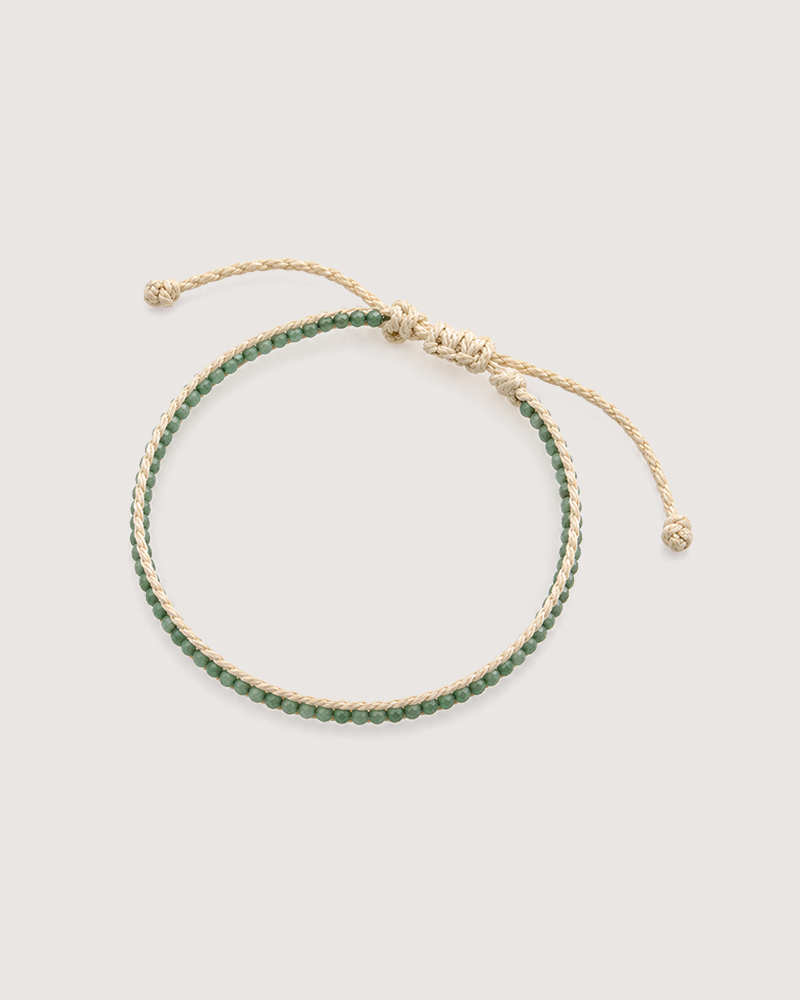 A bracelet made of beige threads and green beads