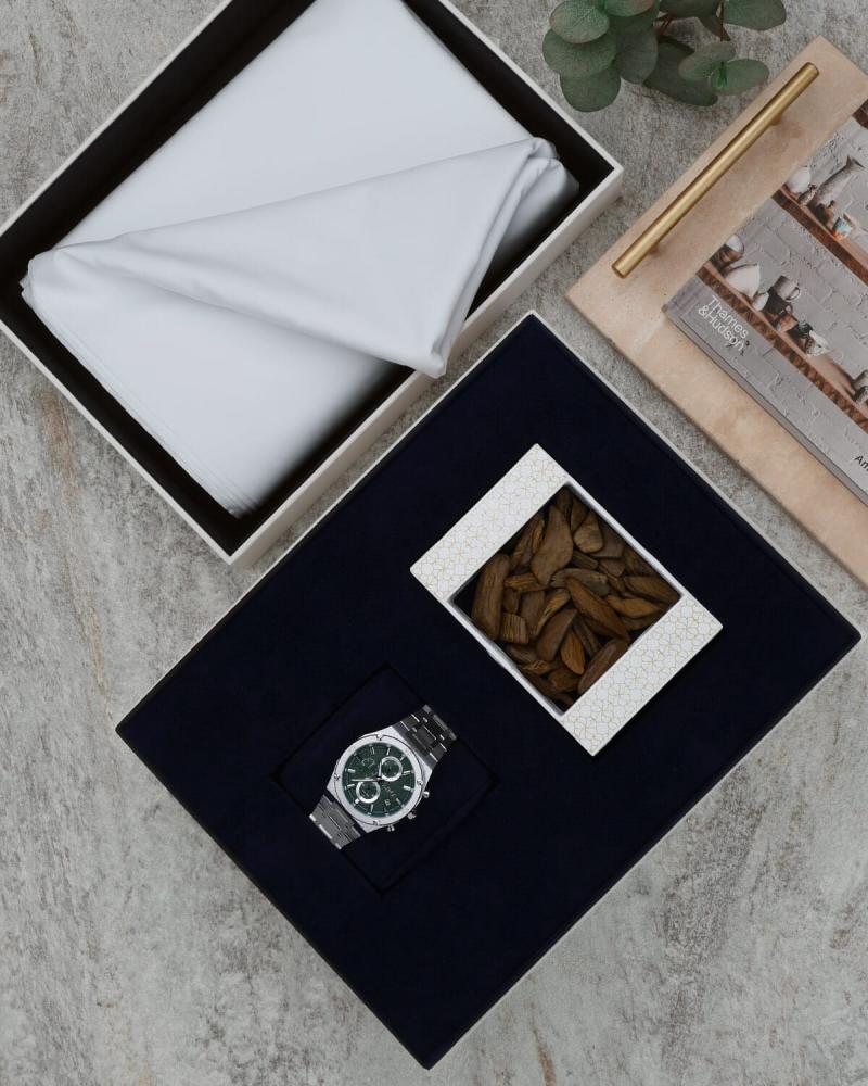 A men's gift set containing a piece of oud, a watch, and a cloth.