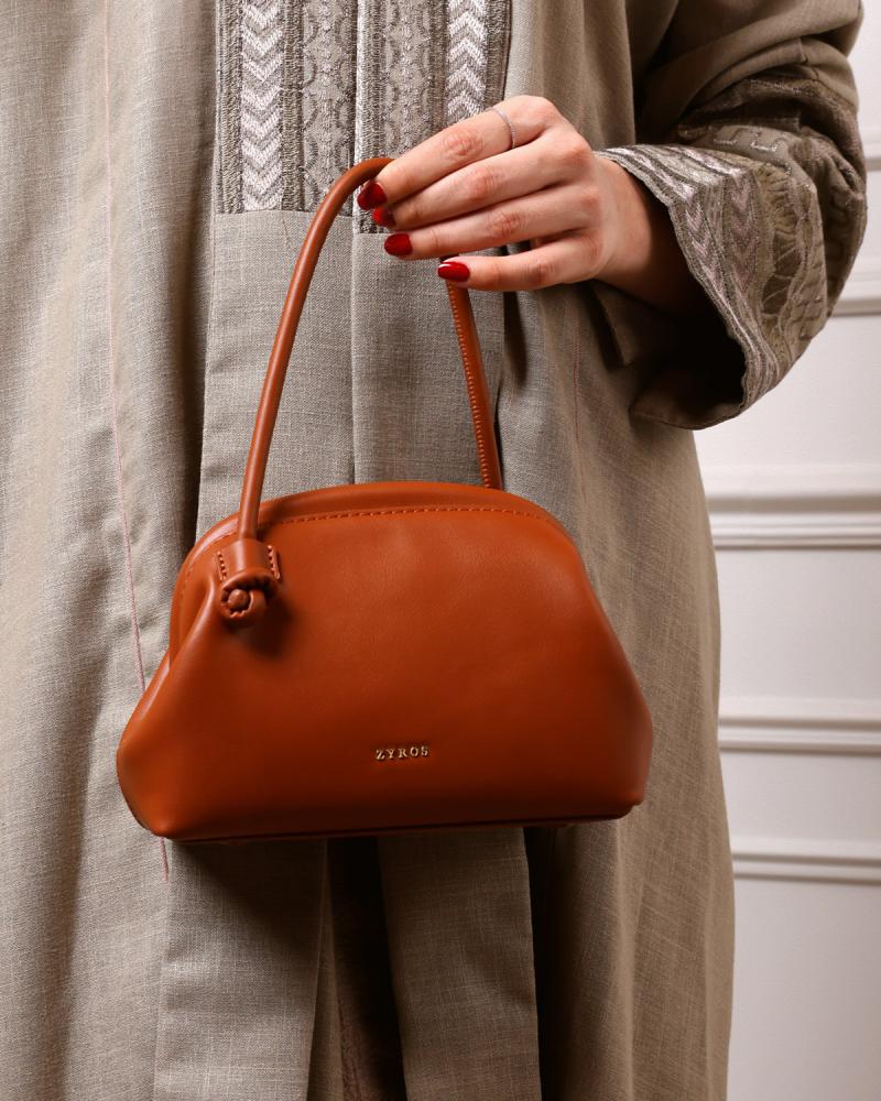 A women's handbag, a work of art, made of brown leather.