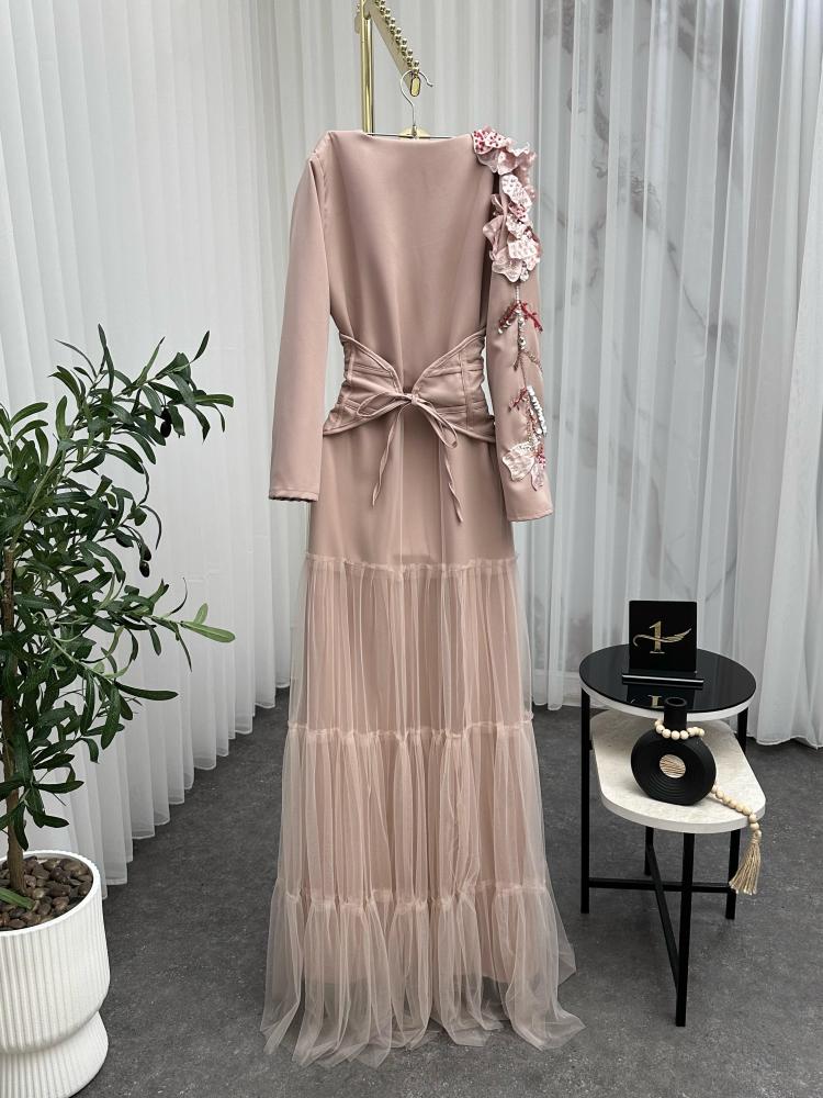 Elegant and soft dress in a nude color with a pinkish tint, decorated with embroidery on the shoulder, long sleeves, with a wide belt at the waist to shape the body, made of Barbie fabric and tulle from Jawhara store