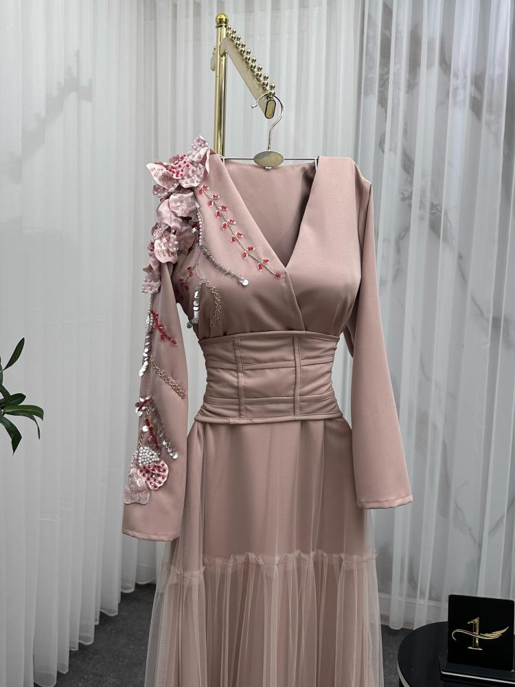 Elegant and soft dress in a nude color with a pinkish tint, decorated with embroidery on the shoulder, long sleeves, with a wide belt at the waist to shape the body, made of Barbie fabric and tulle from Jawhara store