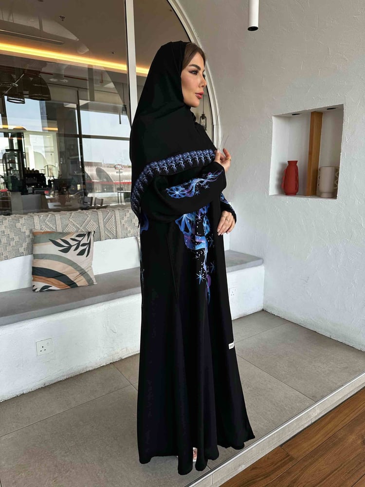 عباية النجم الازرق سوداء مطرزة بنقوش زرقاء على امرأة