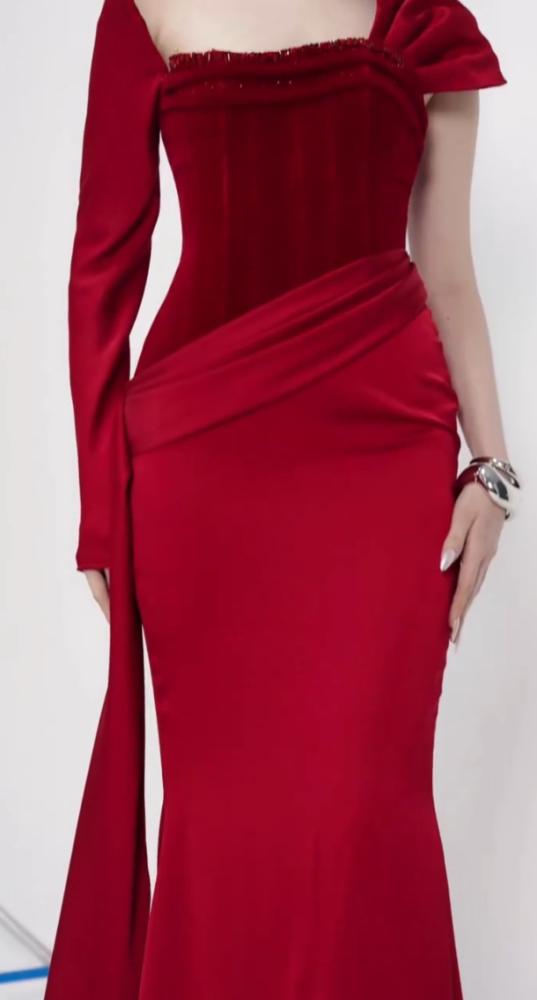 Luxurious red dress with a tight fit that highlights the figure, with an asymmetrical design combining a long sleeve and smooth satin draping on the side. Its beauty is completed by an elegant train that gives a strong presence and a luxurious touch to up