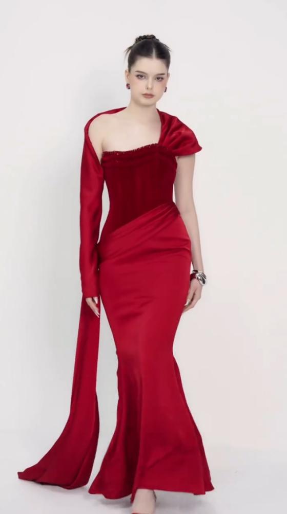 Luxurious red dress with a tight fit that highlights the figure, with an asymmetrical design combining a long sleeve and smooth satin draping on the side. Its beauty is completed by an elegant train that gives a strong presence and a luxurious touch to up