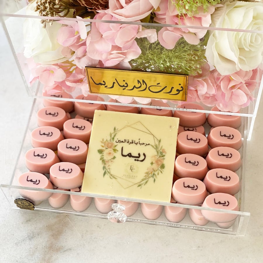 بوكس من الاكريليك مزين بالورد الصناعي يحتوي بداخله على نصف شوكولاته بلجيكية مع اضافة الأسم الخاص