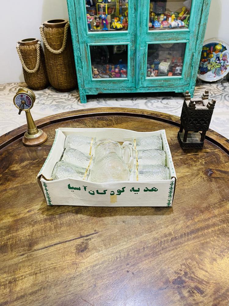 طقم ديكوري من الزجاج المتين جداً بمقاس صغير عبارة عن جيك بإرتفاع ١٥ سم تقريباً وعدد ٦ كاسات بحجم بيالة الشاهي تقريباً؛ قديم ومخزن بالكرتون لم يستخدم